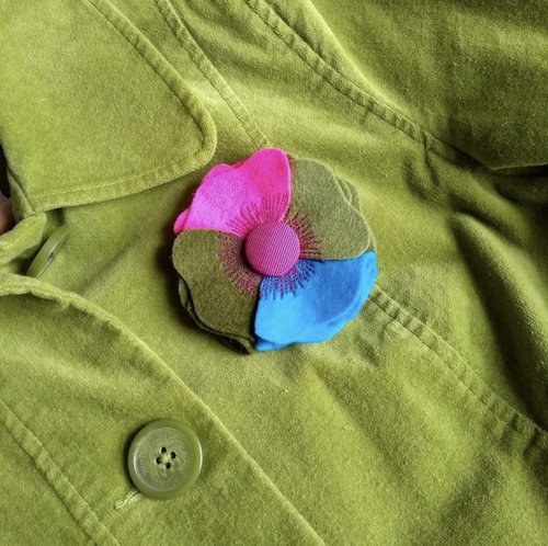 Petunia handmade four colour merino wool felt brooch on a green jacket